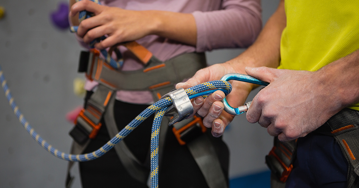 Midsection of athletes adjusting safety harness in fitness club