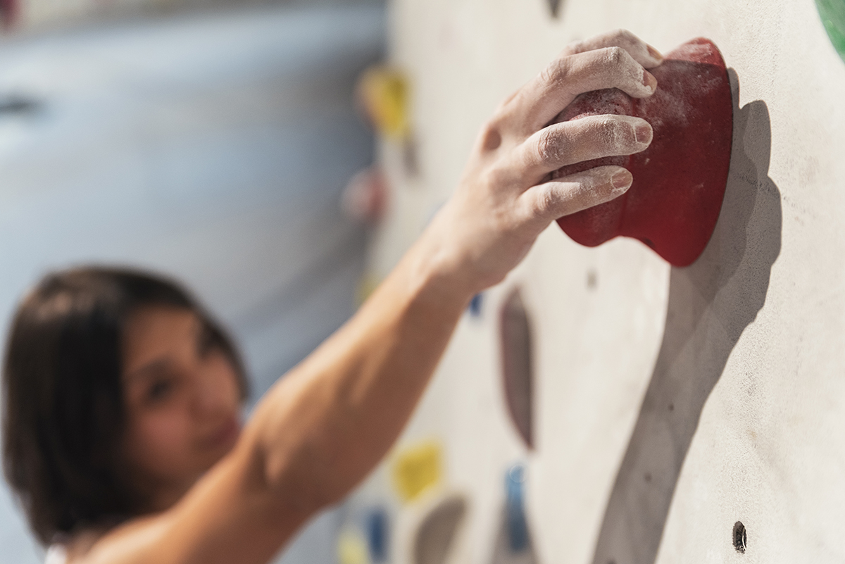 Woman practicing rock climbing on artificial wall indoors. Active lifestyle and bouldering concept.